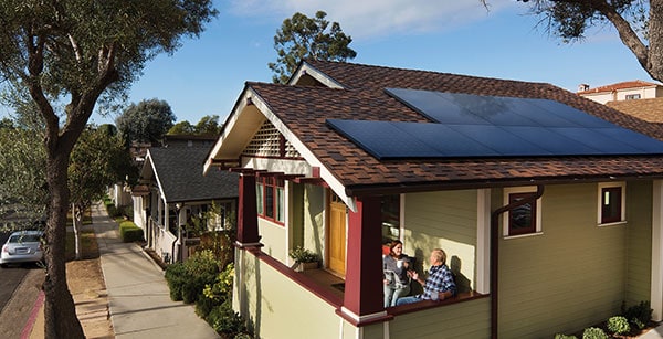 Couple On Front Porch With SunPower Solar Panels On Home