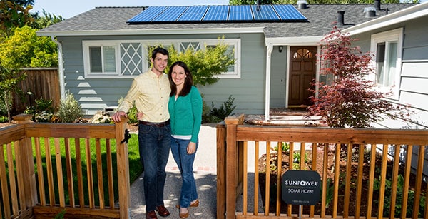 Happy Couple In Front Of Residential Solar Panels 
